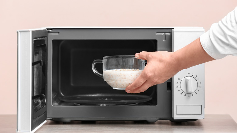 Someone puts a bowl of oatmeal in the microwave