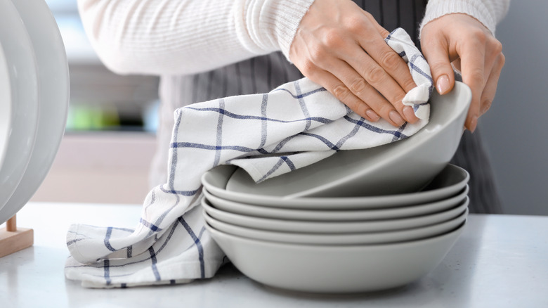 Person drying dishes with a kitchen towel