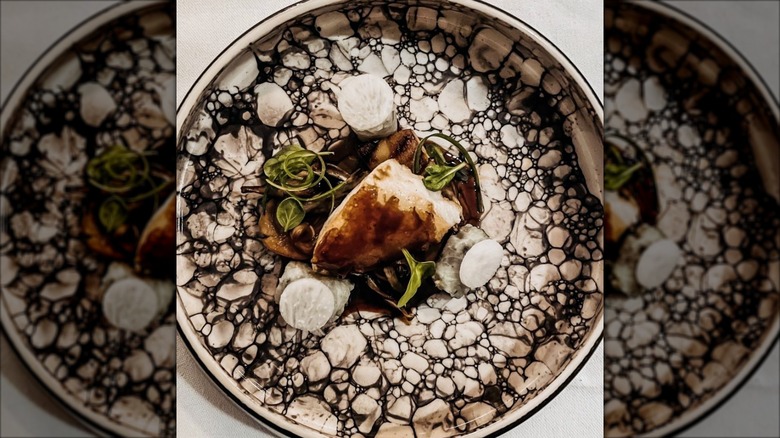 Glacier 51 toothfish charred mushroom sambal on a decorative plate at The Dining Room at Victoria and Albert's