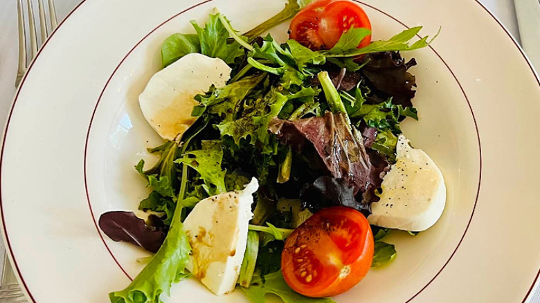 Caprese salad on a white plate with red accents at Chez Grace
