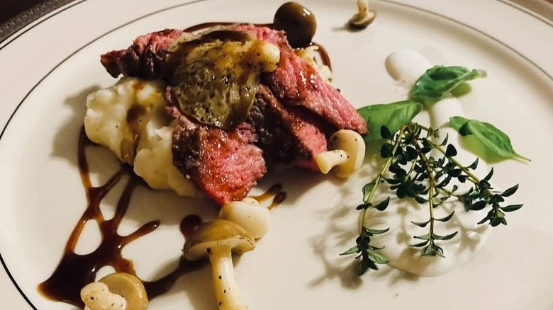 Beef tenderloin with mashed potatoes and mushrooms garnished with fresh herbs at Saltwell Farm Kitchen