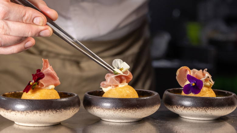 Hand garnishing small dishes with tweezers