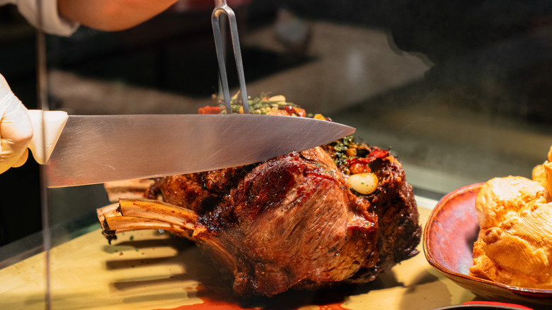 Hands slicing prime rib roast
