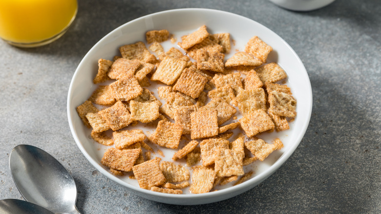 A bowl of cereal, filled with Cinnamon Crunch style square cereal.