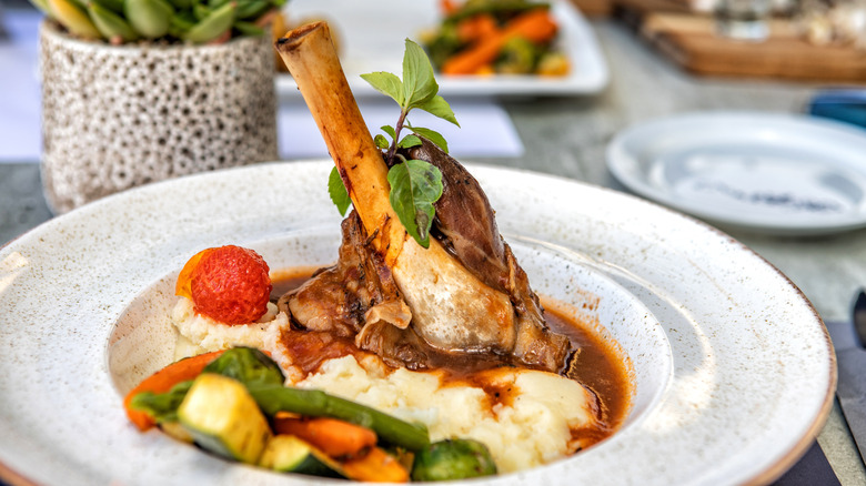 Lamb meat on the bone served with mashed potatoes and roasted vegetables.