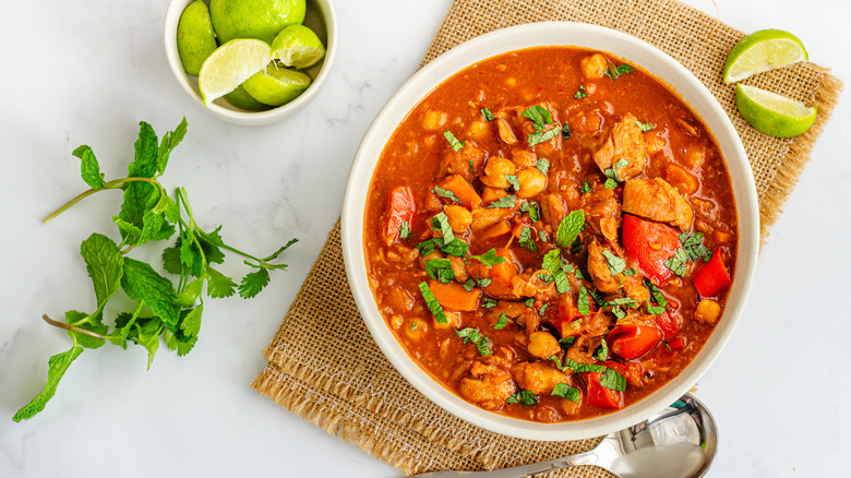 Top view of the traditional Moroccan harira stew, served alongside mint leaves and lime.