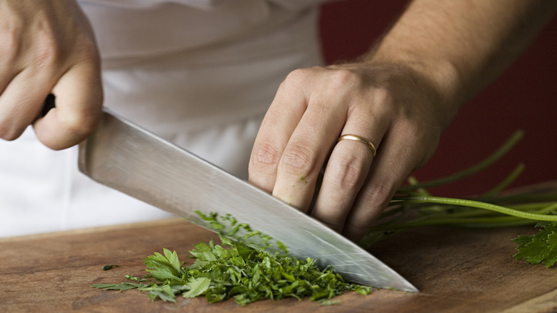 Person using chef's knife to chop herbs