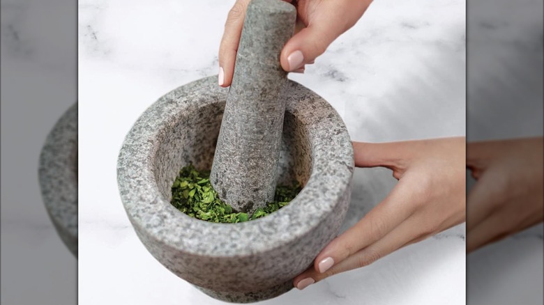A person crushing herbs with the Gorilla Grip mortar and pestle set