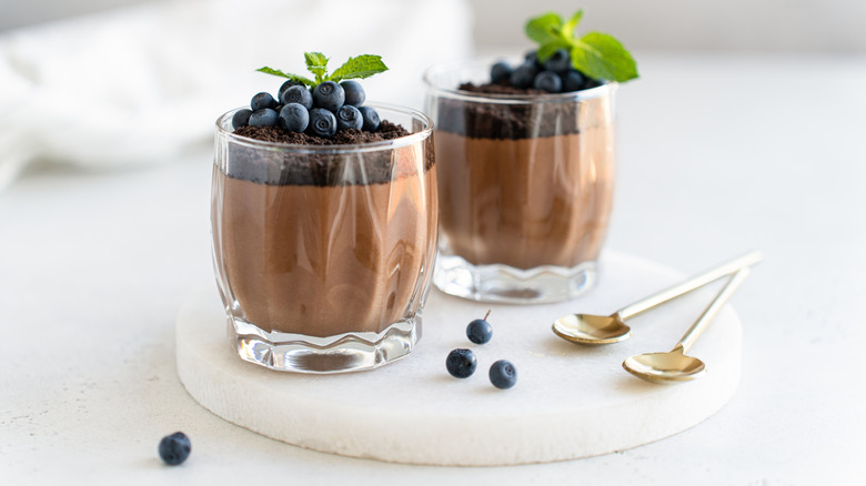 Glass bowls of chocolate mousse topped with blueberries and mint