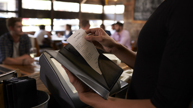 server prepaaring the bill inside of restaurant
