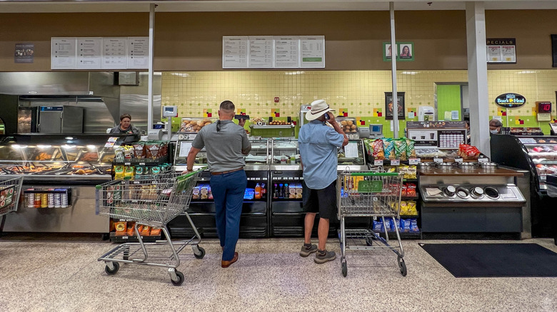 Two men with shopping carts waiting at the Publix deli counter