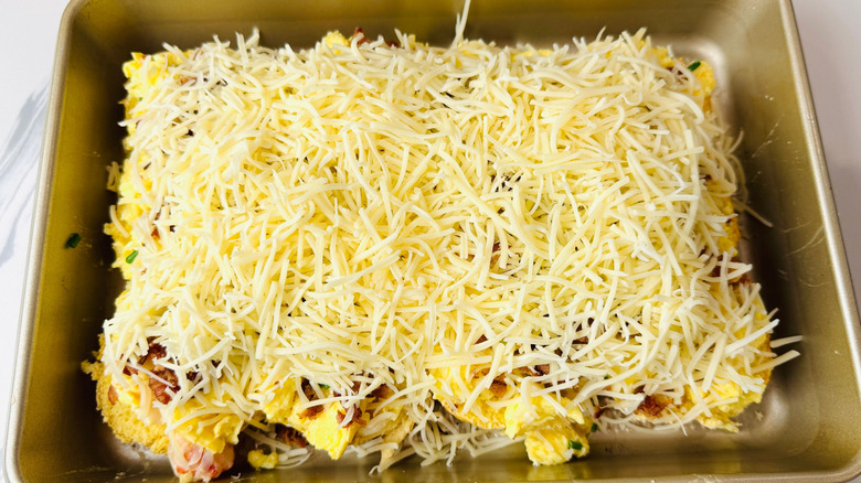 Scrambled eggs, bacon, and shredded cheese layered in baking pan