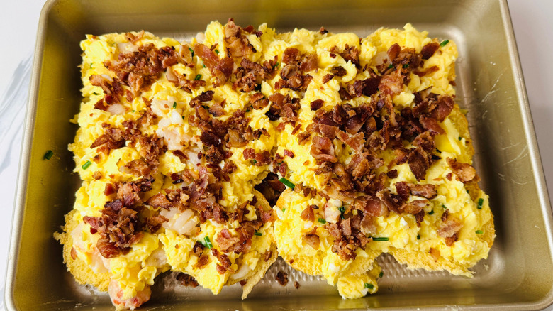 Crumbled bacon on top of scrambled eggs in baking pan