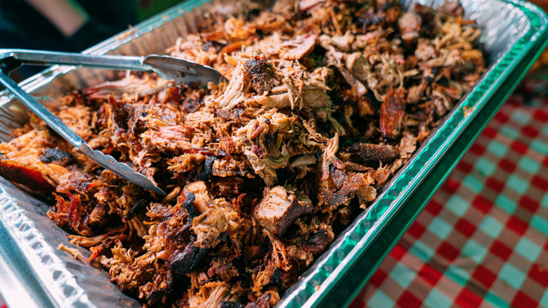 Closeup of big batch of pulled pork in aluminum tin