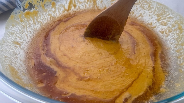 Wooden spoon stirring brown butter into pumpkin puree mixture