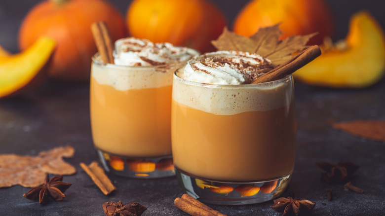 pumpkin spice lattes with whipped cream and cinnamon sticks