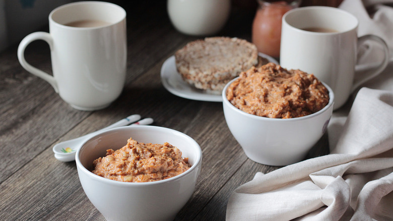 overnight oats in bowl with cups of coffee and rice cakes on plate