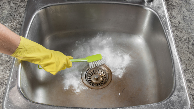 Gloved hand scrubbing kitchen sink