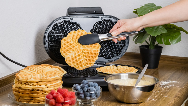 person making waffles in waffle maker with berries