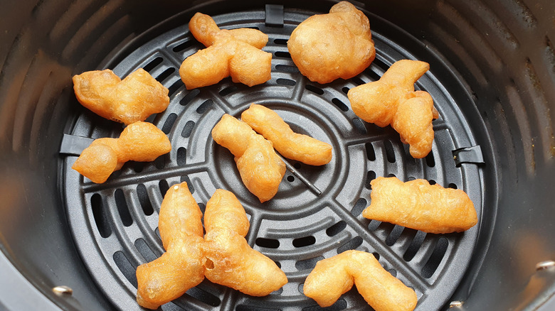 Overhead view of fried dough in the basket of an air fryer