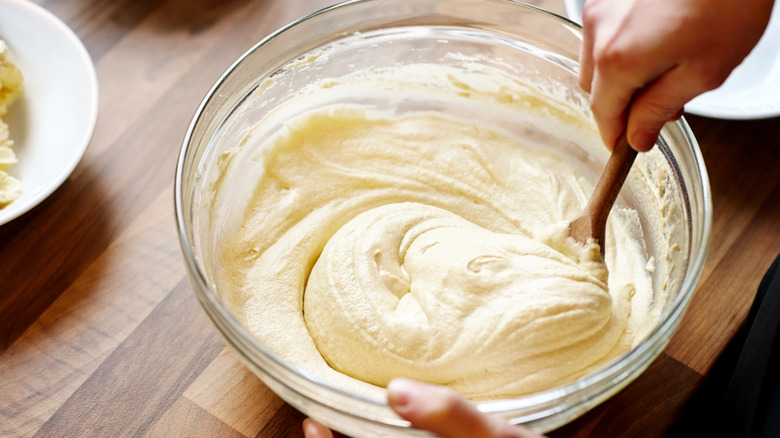Overhead view of person mixing cake mix in a bowl with a spatula