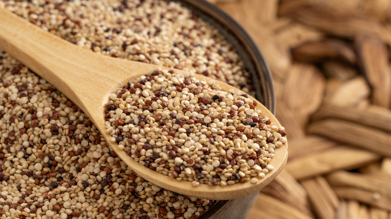 Wooden bowl filled with quinoa and a wooden spoon