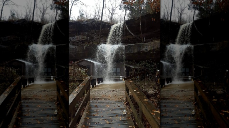 Waterfall pouring over a building set into a rocky cliff face