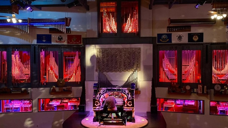 Organ on stage with pipes on the wall and bright red lights
