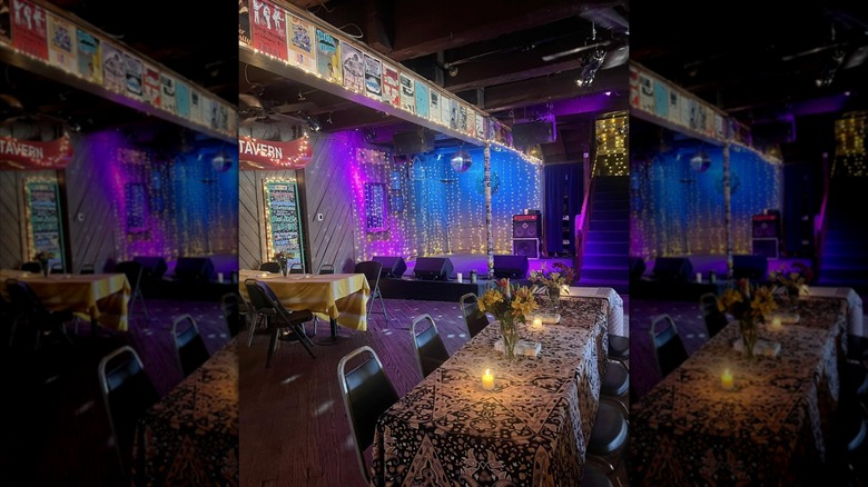 Long tables with flowers and hanging lights with a stage in the background