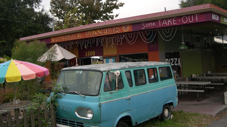 Exterior of a building with a colorful umbrella and an old blue van