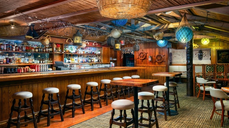 Inside of Trader Vic's with a tiki bar, stools, and hanging lights
