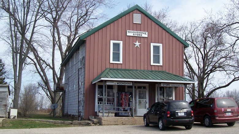 Exterior of Moonshine Store with a red front, green awning, and several cars
