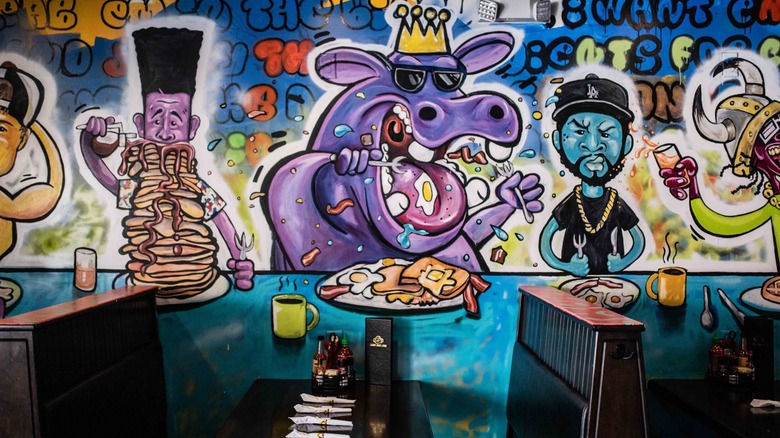 Graffiti-style wall showing people and animals eating brunch dishes