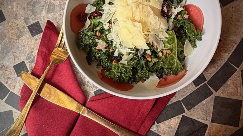 Kale salad on a table with gold utensils
