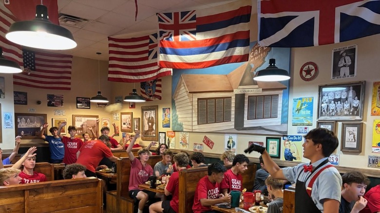 Server throwing rolls to customers in a busy dining room
