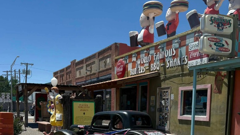 Exterior of Sparky's with multiple statues and a classic car