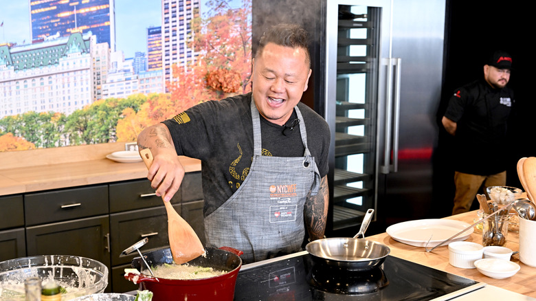 Jeff Tila cooking in front of an audience, a steaming Dutch oven in front of him