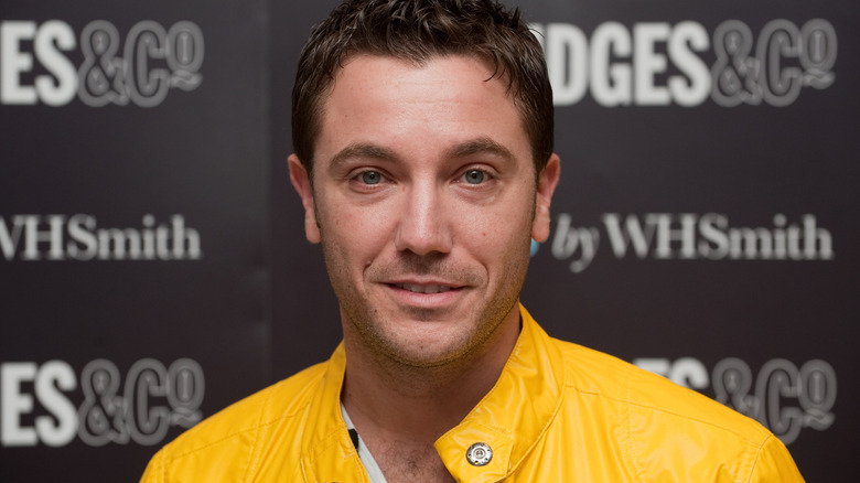 Portrait shot of Gino D'Acampo wearing a bright yellow jacket.