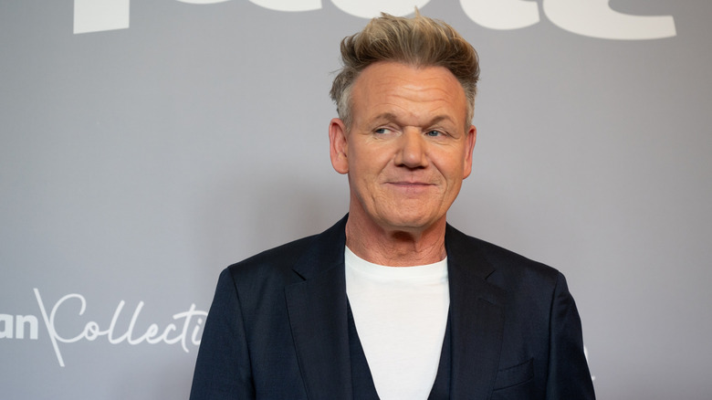 Gordon Ramsay looks toward the side against a light gray background.