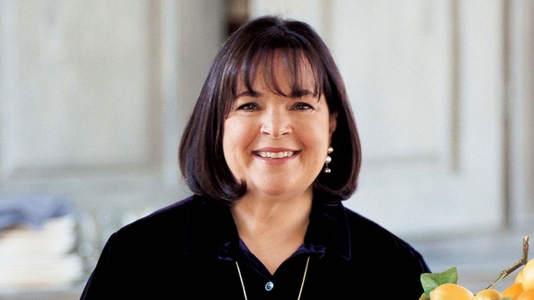 Ina Garten in a black button up with a white kitchen background