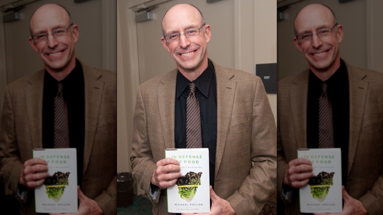 Michael Pollan holding a copy of his book, "In Defense of Food"