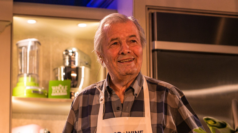 Jacques Pépin in a plaid shirt and apron in a kitchen