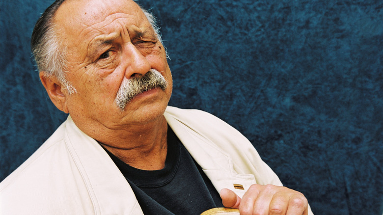 Jim Harrison poses in front of a blue background