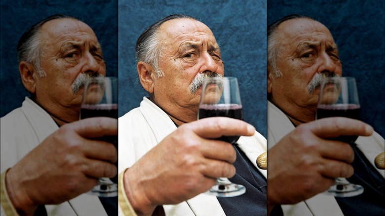 Jim Harrison holding a glass of red wine