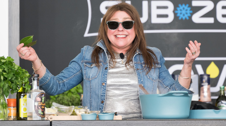 Rachel Ray smiling while standing behind counter and cooking
