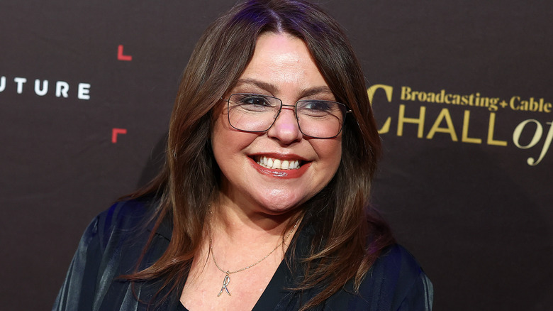 Rachel Ray smiling in a navy outfit with glasses