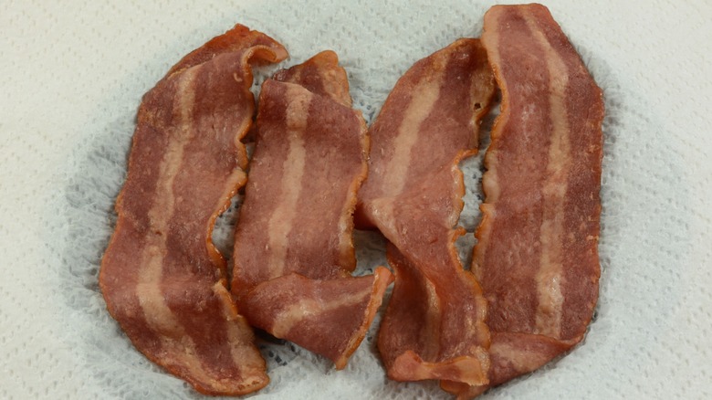 four slices of microwaved bacon on a paper towel