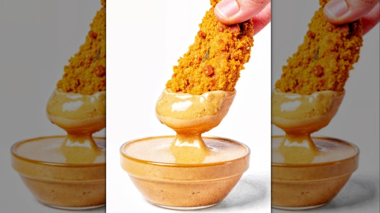 A chicken tender dipped in honey mustard sauce