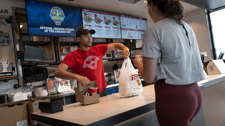 A worker brings out an order to a customer at Raising Cane's