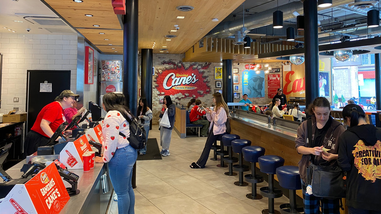 Raising Cane's restaurant interior showing tills, staff, and customers